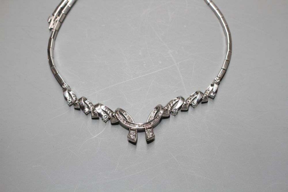 A modern 750 white metal and diamond set open scroll necklace,